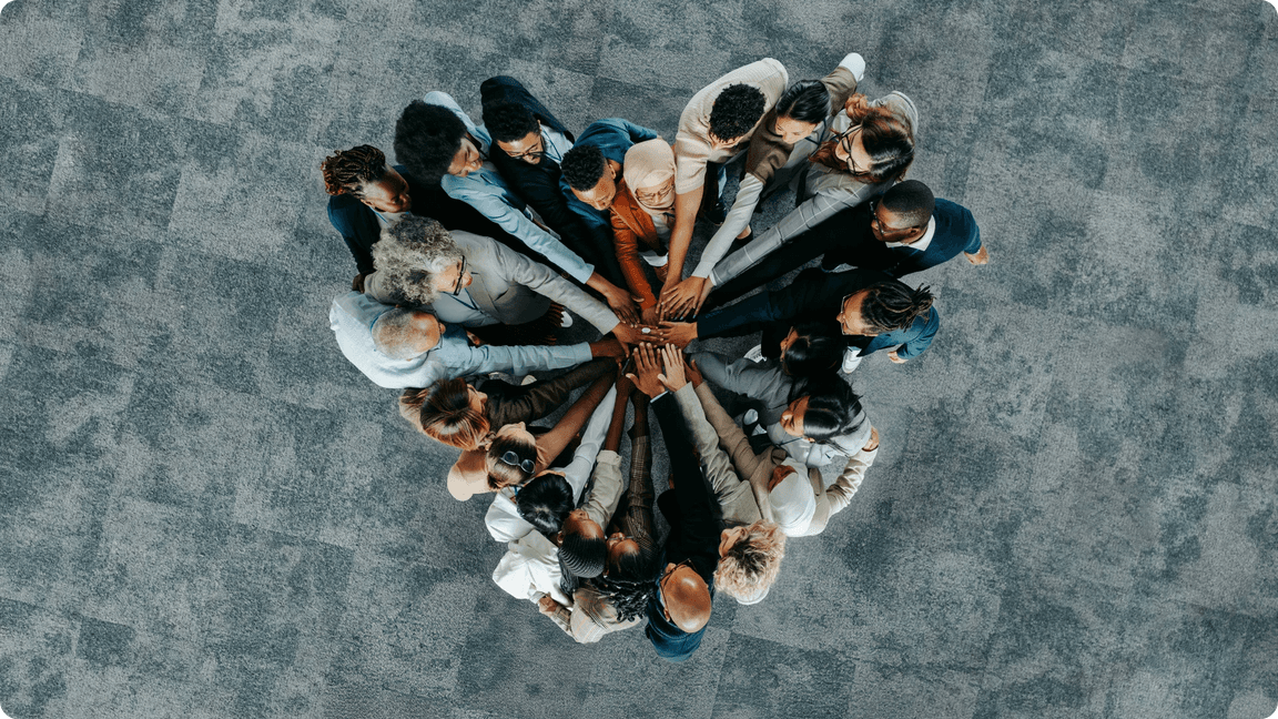 Overhead view of a diverse group standing in a circle with hands joined together.
